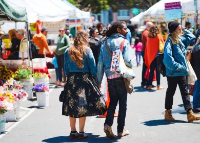 Man and Woman walking away from camera with an outdoor marketplace in the background