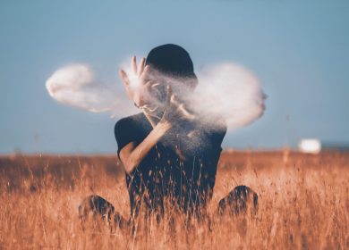 Person in field of hay behind a cloud of puff wearing black