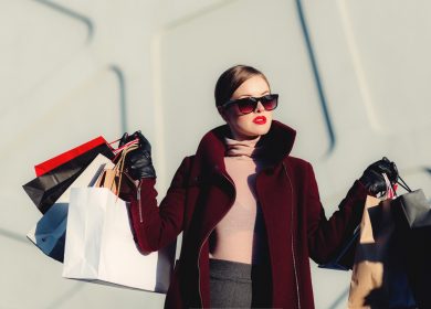 Woman wearing coat and sunglasses carrying bags