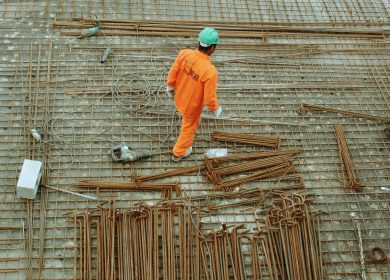 Man walking around pipes with a hard hat
