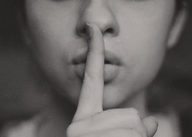 Person holding finger up to lips in a quieting motion