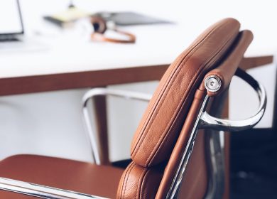 Brown chair with chrome armrests in front of a desk