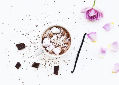 View on top of cup of cocoa next to flower with petals detached