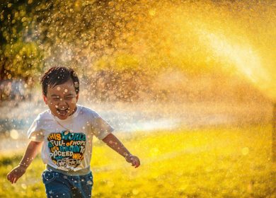 Boy running through water with white t-shirt and smile