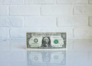 One Dollar Bill against a white brick background