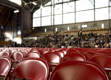 View of chairs set up with crowd in stands in the background