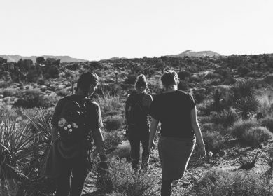 Three people walking through a field in black and white