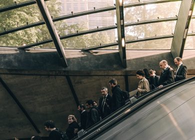 People on an escalator with a glass ceiling in the background