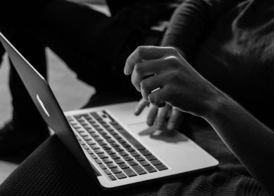 Black and White view of Laptop with person's hand up and the other on the touchpad