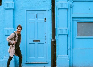 Man walking in front of a blue building with a blue door