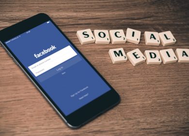 Smartphone with Facebook login screen on it next to scrabble tiles that have formed the words Social Media